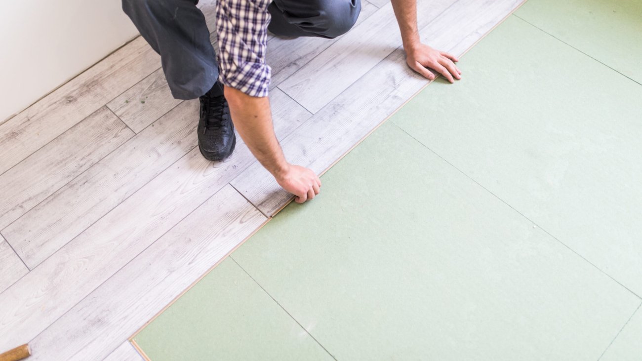 Young worker laying a floor with bright laminated flooring boards